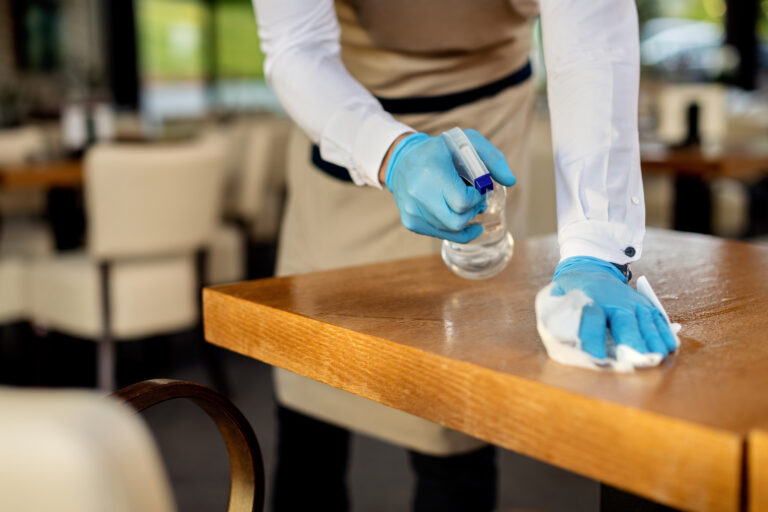 Close-up of waiter disinfecting cafe tables after work
