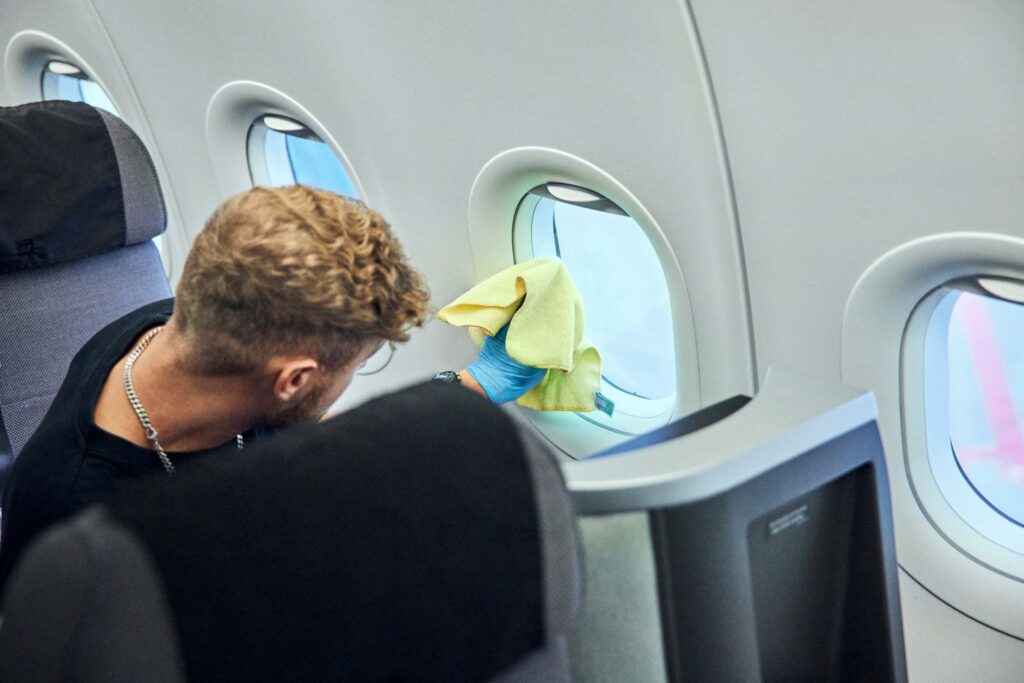 SERWIZ medarbejder tørrer et flyvindue af i kabinen